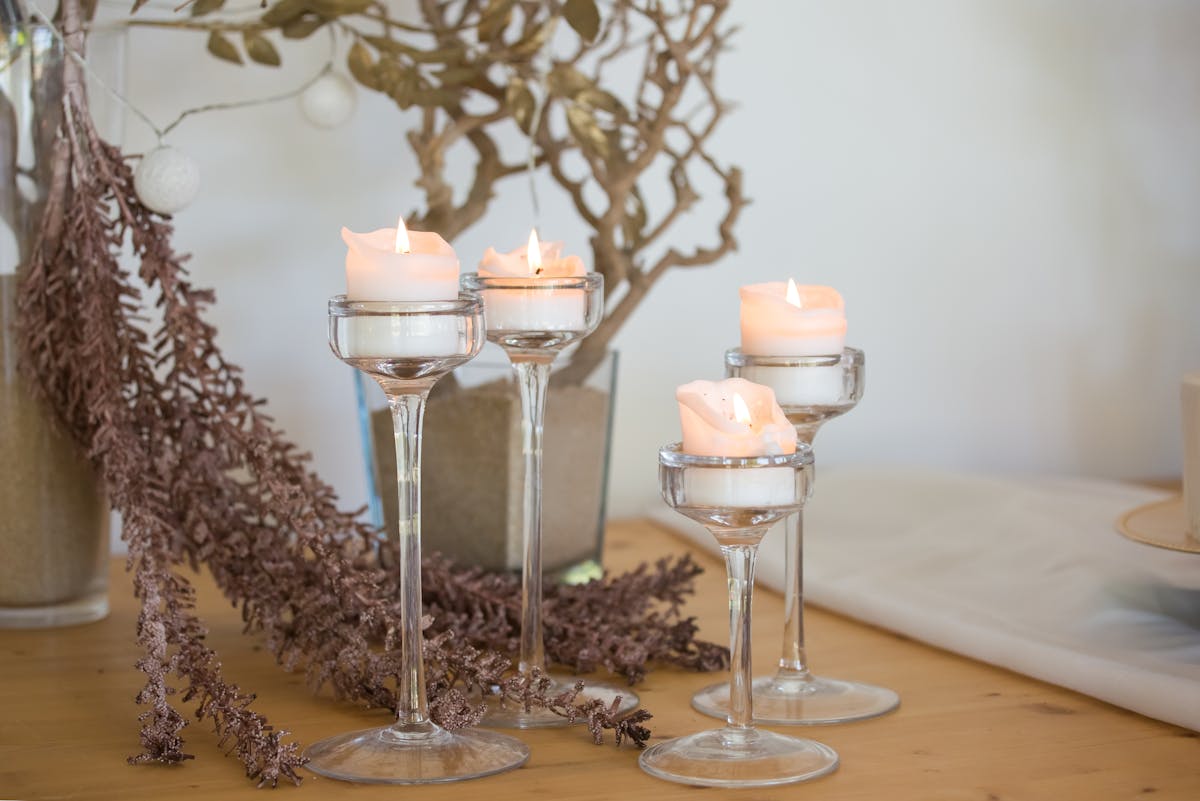 Stikla svečturi ar degošām svecēm uz koka galda elegantā kāzu noformējumā